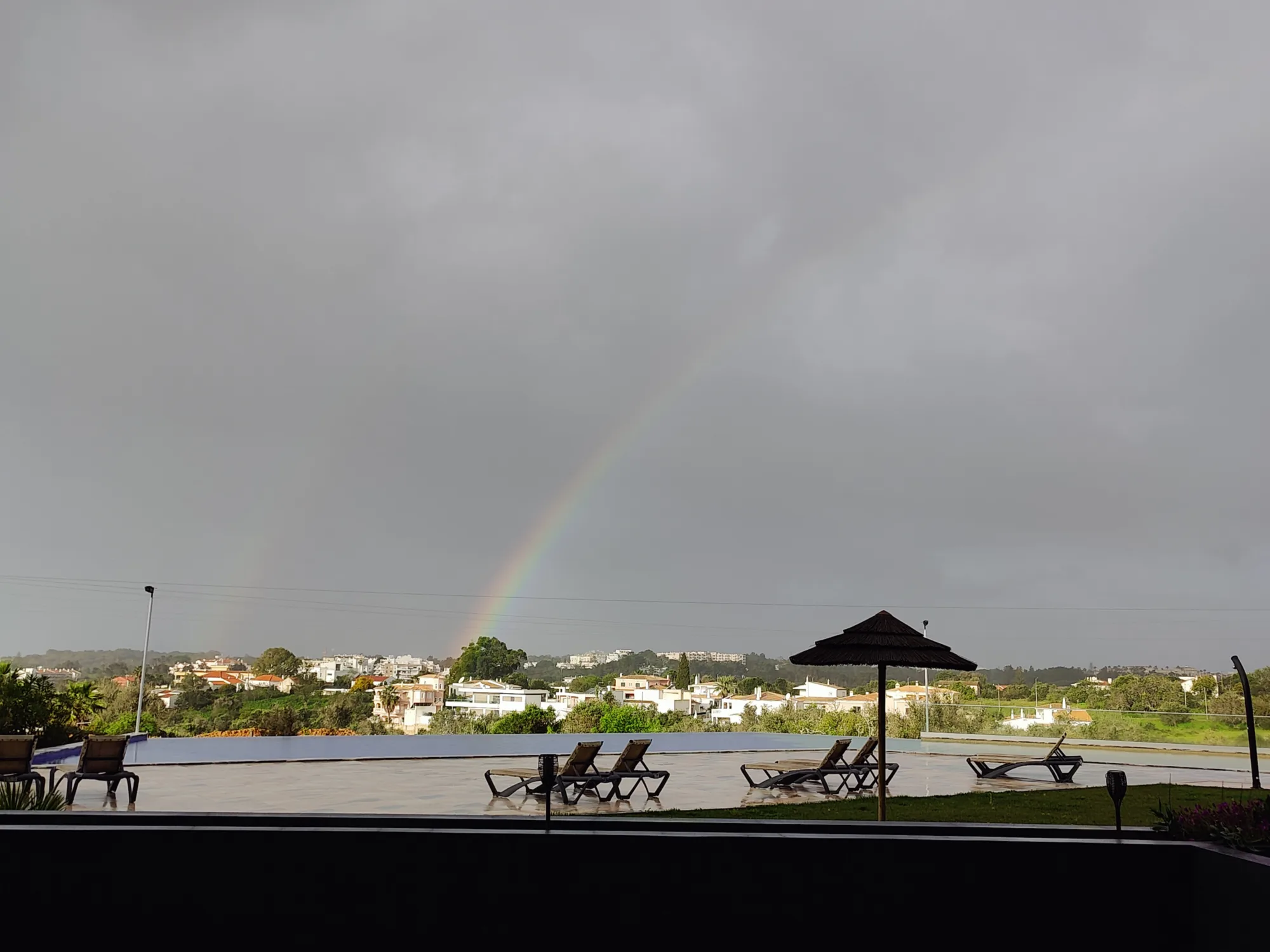a rainbow is seen in the sky over a swimming pool
