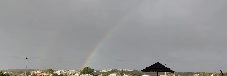 a rainbow is seen in the sky over a swimming pool