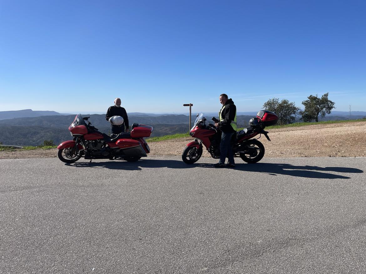 2 motorcycles and a man and a women up in the mountains with a view